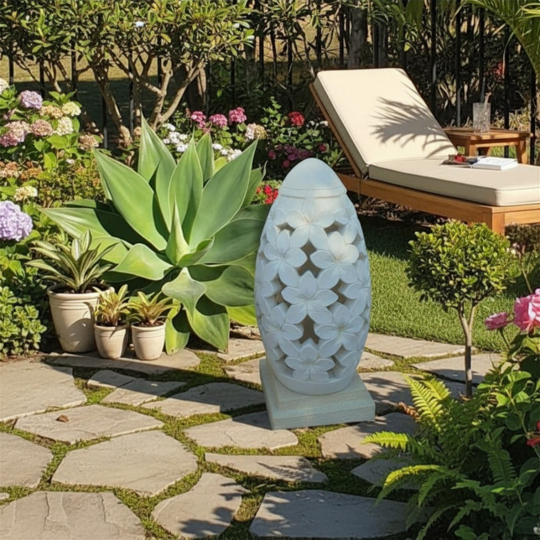 Decorative garden lantern on a stone path with plants and a lounge chair in the background