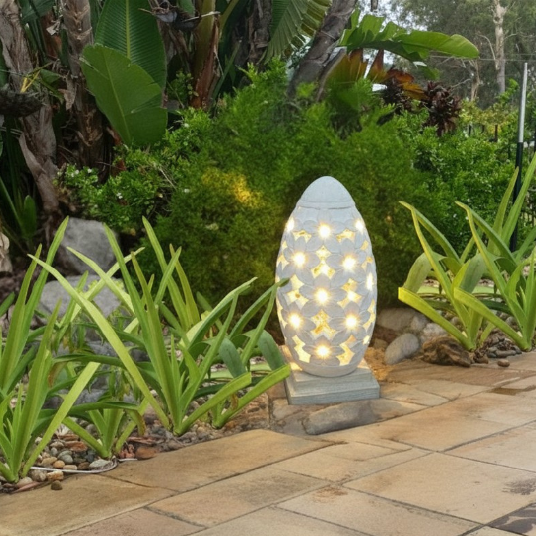 Decorative garden light in a garden setting with plants and stones.