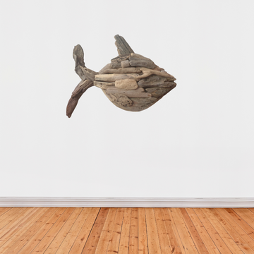 A wall-mounted driftwood fish art piece in a boho style, displayed against a white background with wooden flooring.