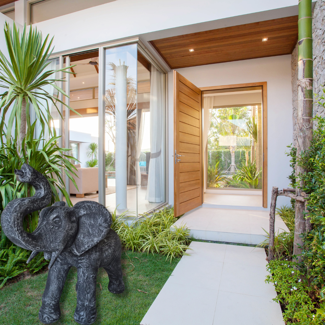 Elephant statue in a green garden infront of a home entry 