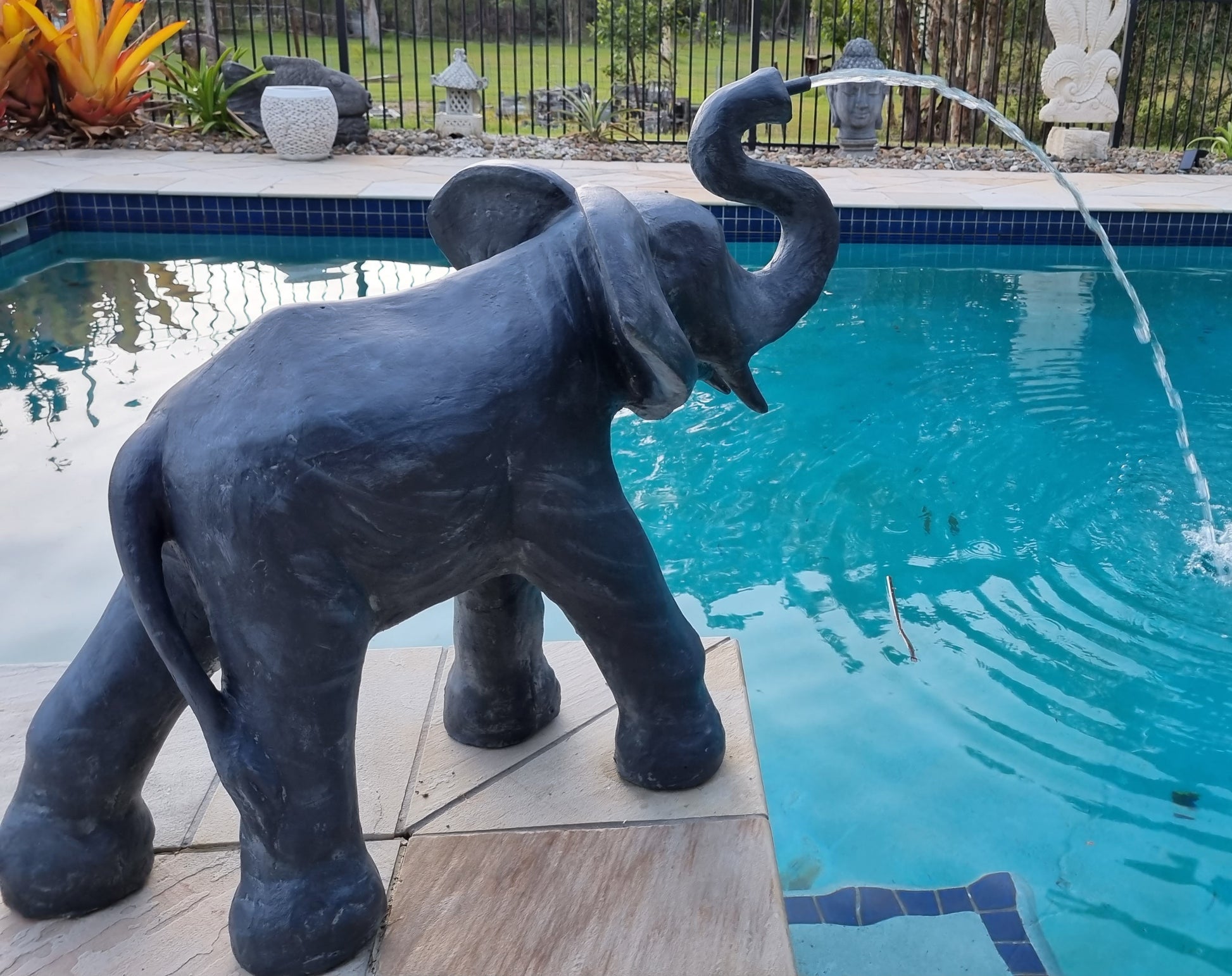 Elephant Statue water spilling into a pool side view 