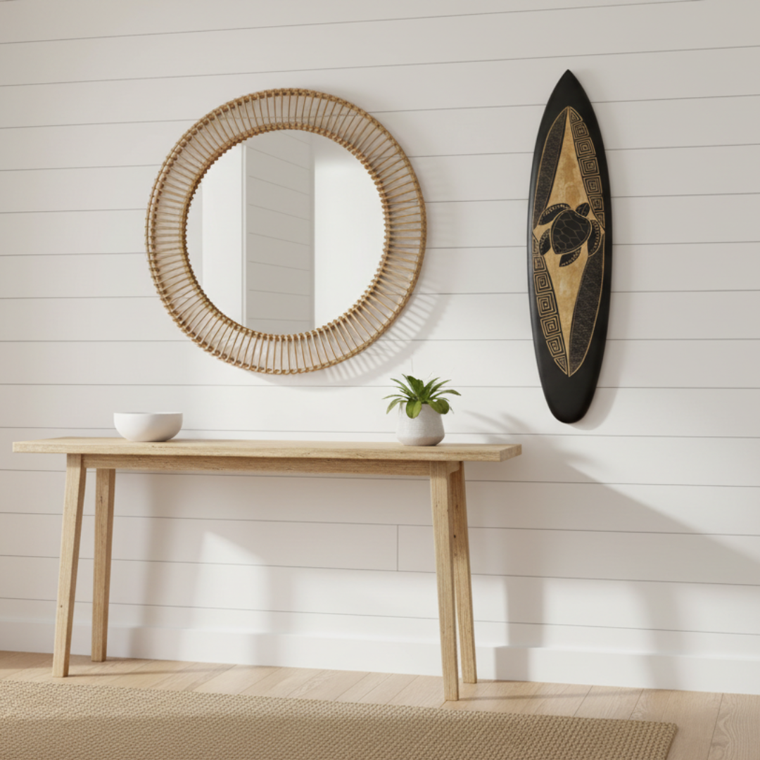 Black wooden surfboard with a carved sea turtle centrepiece, wave scale pattern and geometric Greek key border in natural tones on a white background