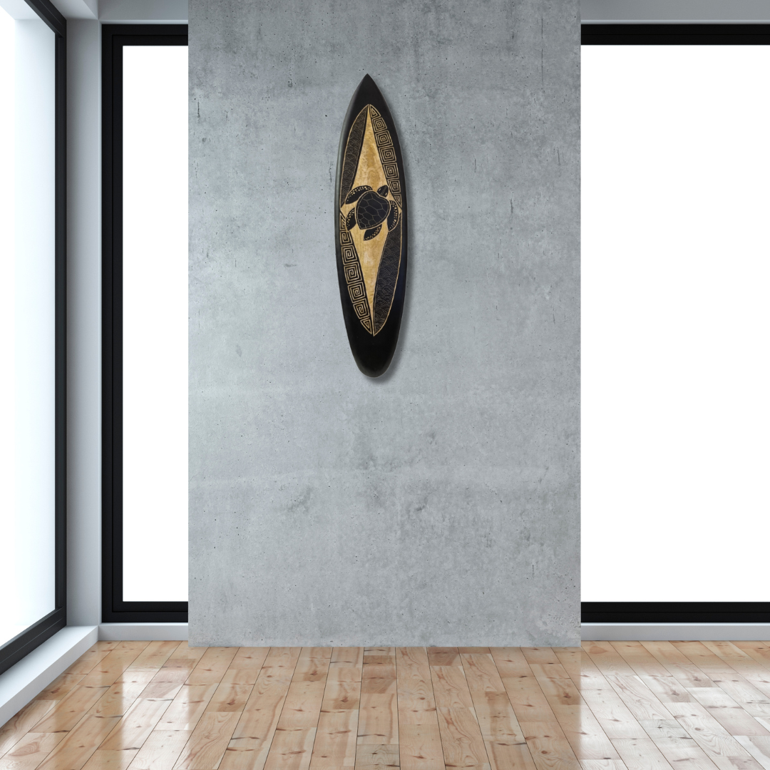 Hand-carved wooden surfboard wall art featuring a turtle in the midsection with decorative scrolls accents, displayed hanging vertically on a soft grey wall