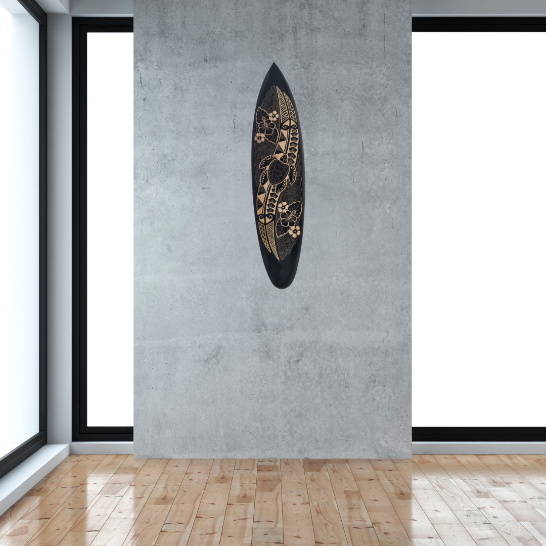 Hand-carved wooden surfboard wall art featuring a carved turtle, hibiscus flowers, and decorative floral scrolls, displayed hanging vertically on a soft grey wal