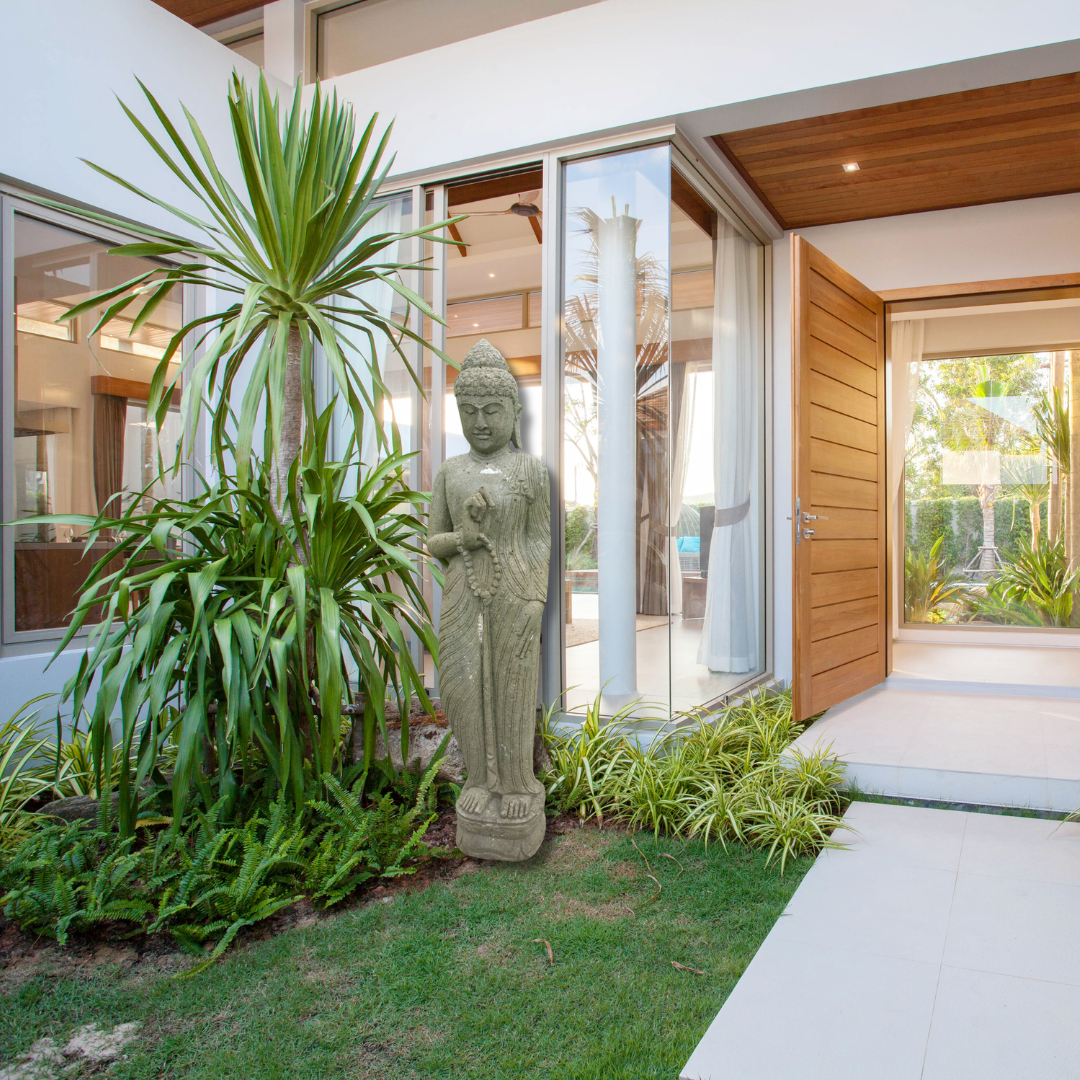 Exquisite Green Stone Buddha statue styled at a modern home entrance surrounded by tropical garden plants and lush greenery