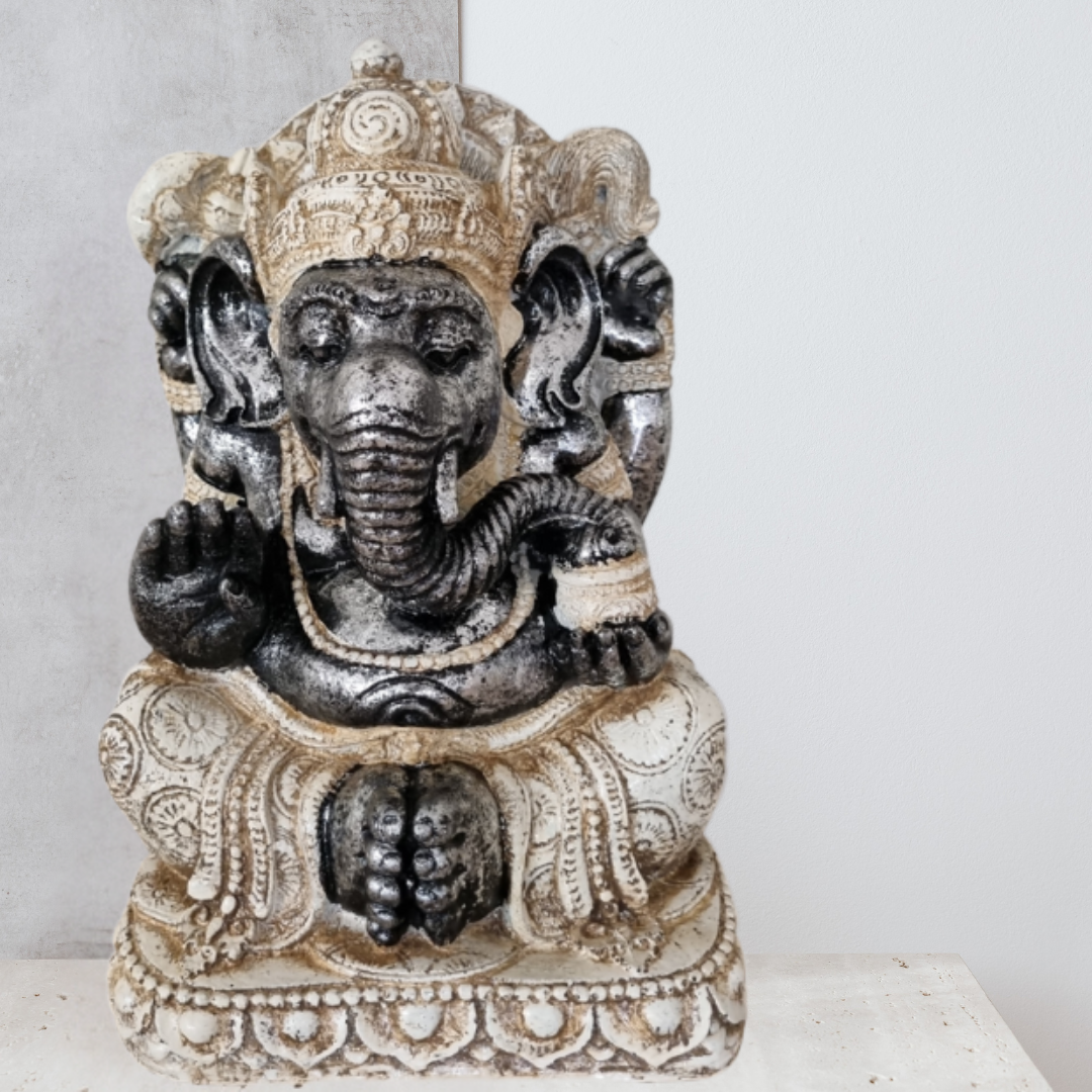 Decorative statue of a seated figure with elephant head on a white surface