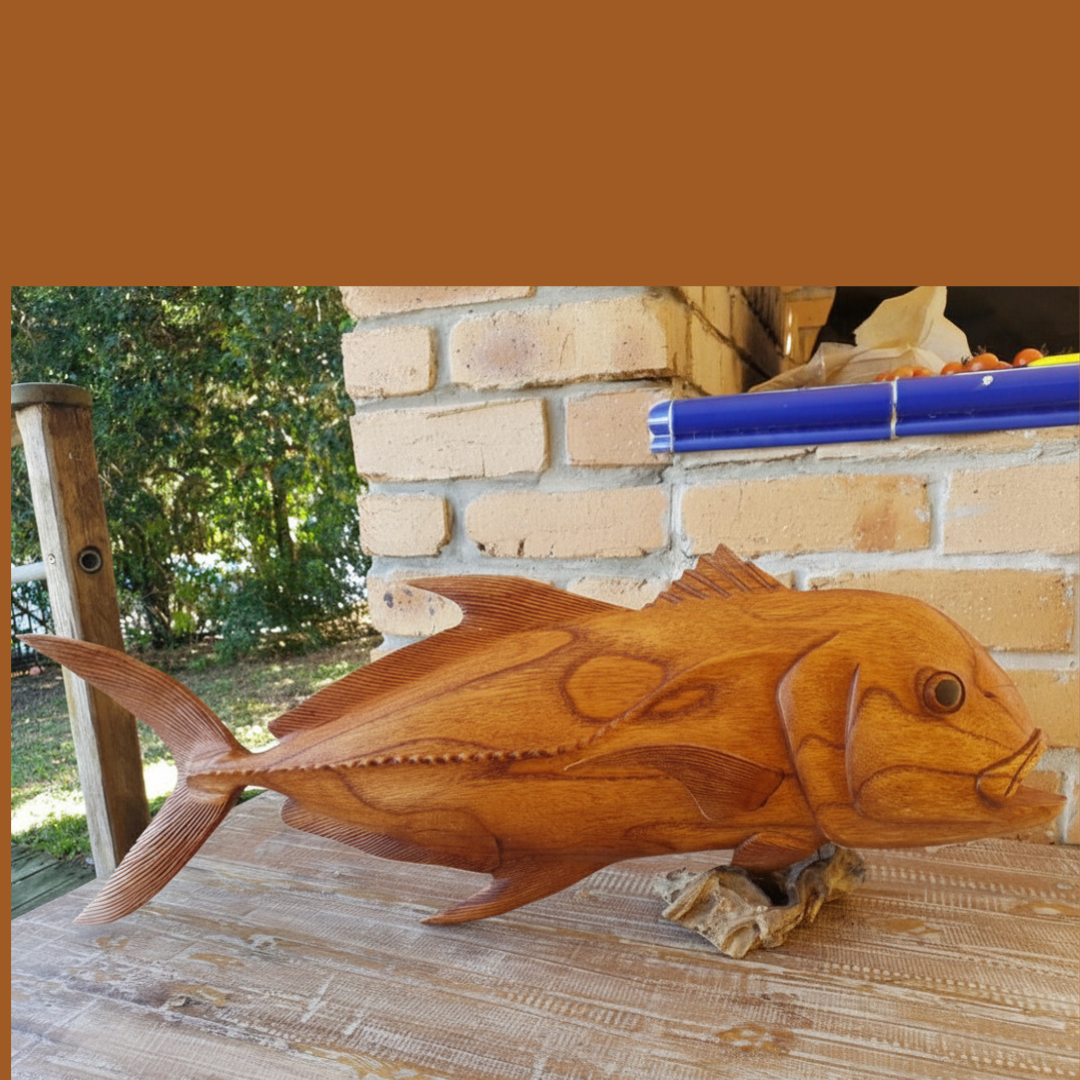 Giant Trevally wooden fish carving on driftwood stand – displayed outdoors on timber deck, showing true 80cm scale, handcrafted coastal sculpture