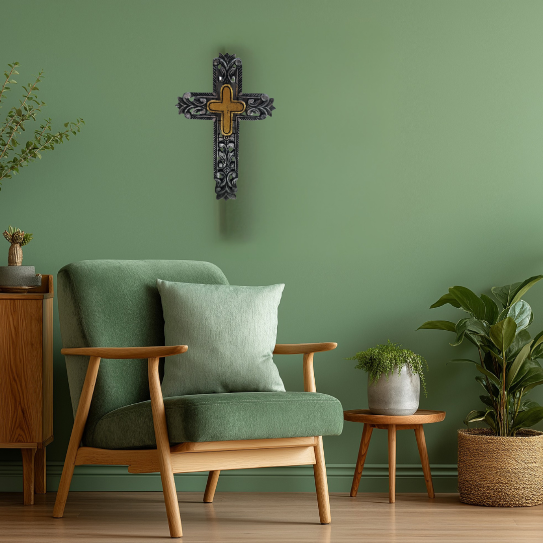 Green armchair with wooden frame against a green wall with a decorative cross, surrounded by plants.