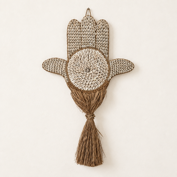 Hamsa Hand Wall Art with natural cowrie shells and a brown seagrass tassel on a warm ivory background
Coastal lifestyle scene: