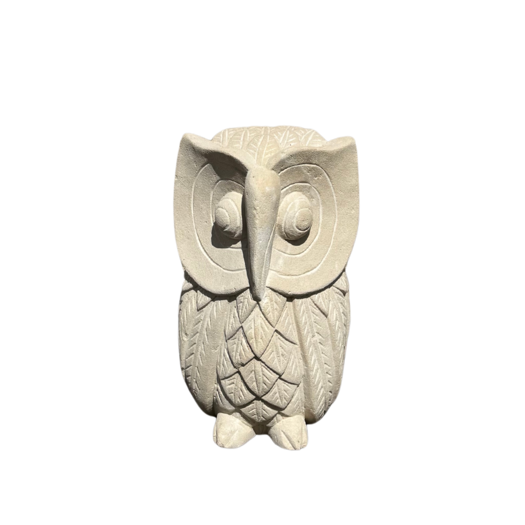 A carved stone figurine in a light beige or off-white color, featuring detailed engravings on its feathers and facial features, set against a plain white background.