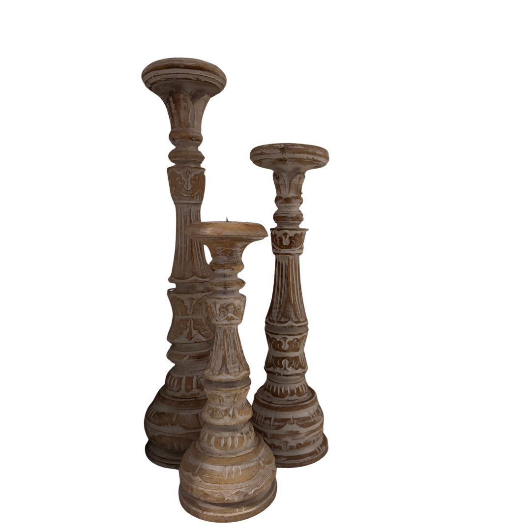 Set of three wooden candle holders with intricate designs on a white background