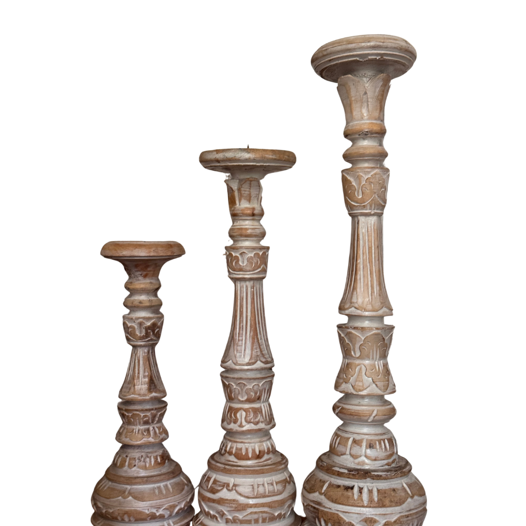 Three wooden candle holders with intricate carvings on a white background