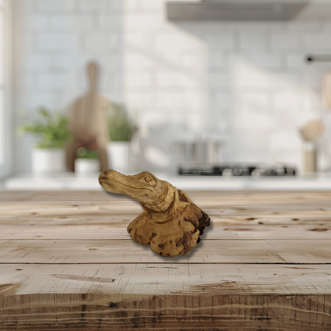 Hand-carved wooden crocodile sculpture displayed on a wooden table in a coastal home interior.