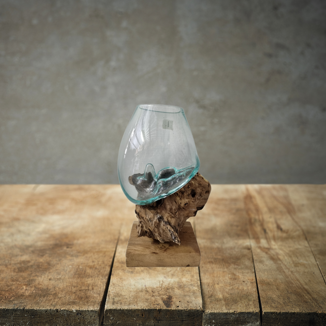 Glass vase with pebbles on a wooden base against a gray background