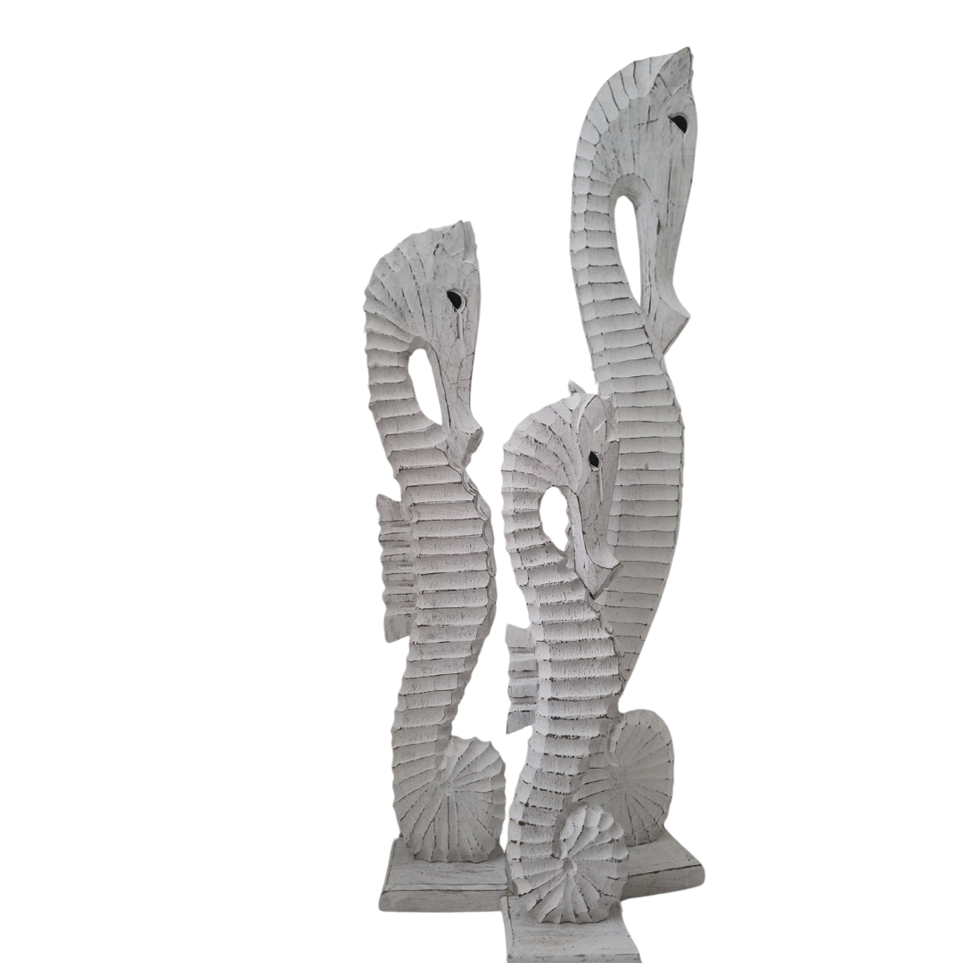 A set Seahorse Wooden Carved Statues, in three different sizes small medium and large on a white back wall 