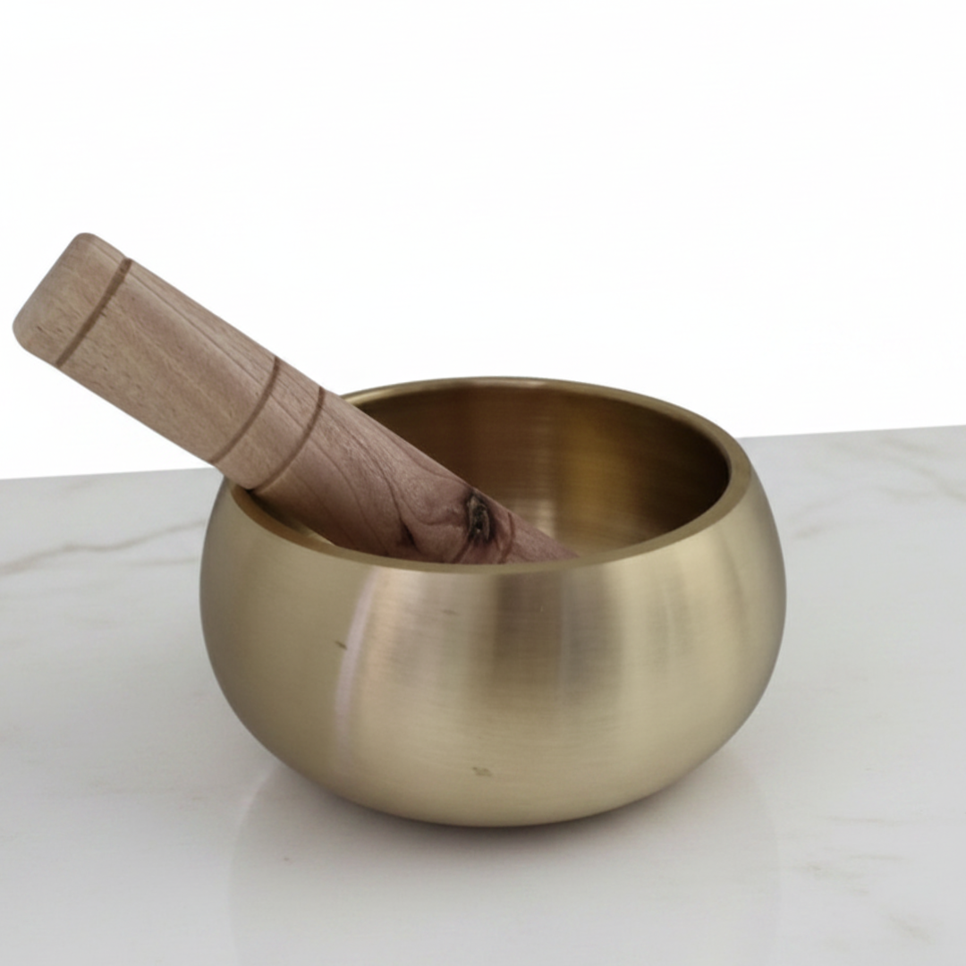 Handcrafted Brass Singing Bowl with wooden mallet resting inside, photographed on a white marble surface against a clean white background