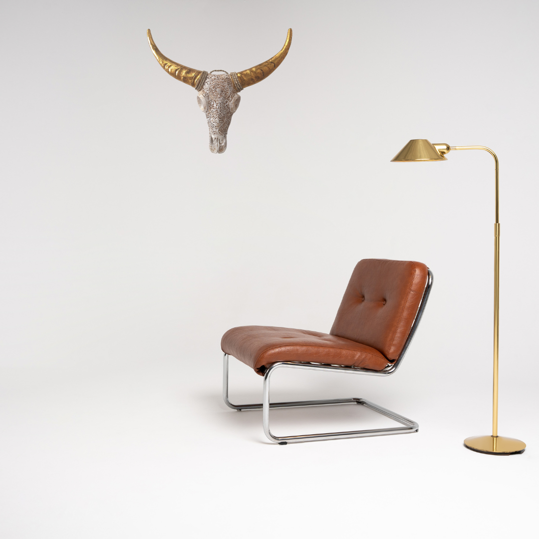 Brown leather chair with a gold floor lamp and bull skull on a white background