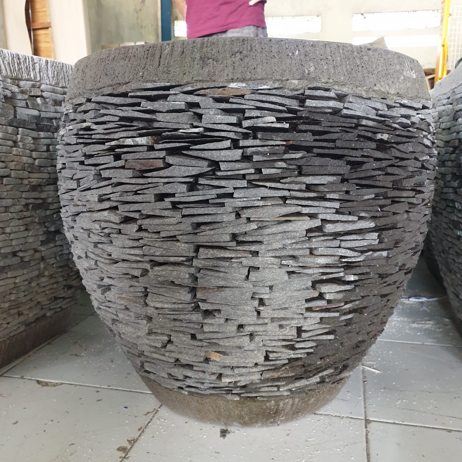 Decorative stone pot with a textured surface on a tiled floor.