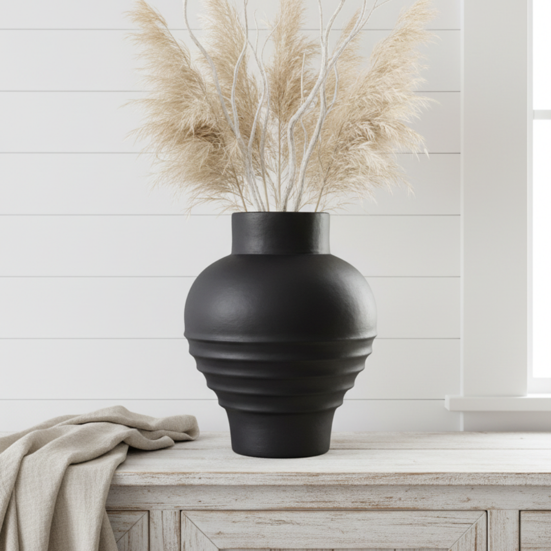 Large matte black globe vase with dried pampas grass on a whitewashed timber sideboard in a bright coastal living room