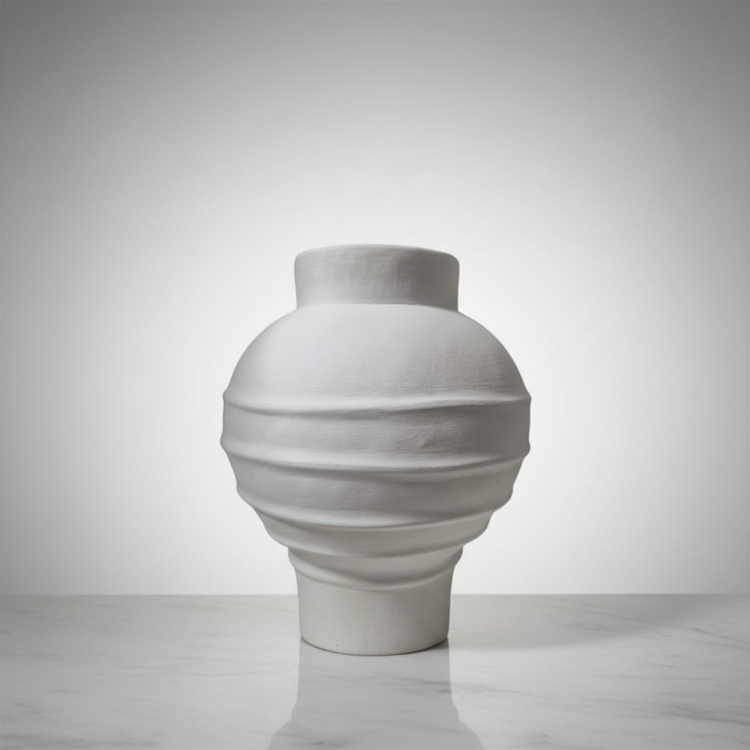 White matte terracotta vase with a rounded globe form and textured ribbed surface on a neutral grey background