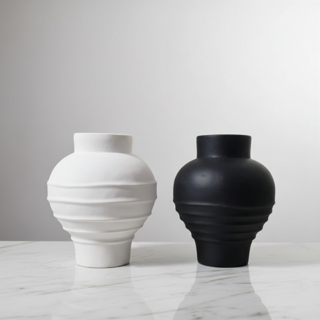 Two vases, one white and one black, on a marble surface with a gray background.