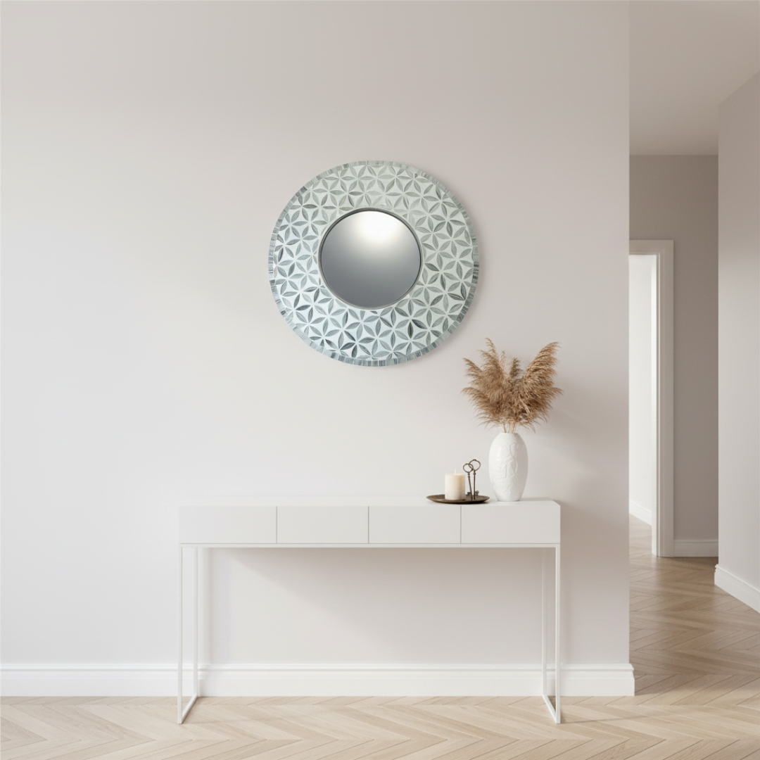 Handmade round mosaic mirror in silver grey above a white console table with pampas grass and candle in an elegant coastal hallway 

