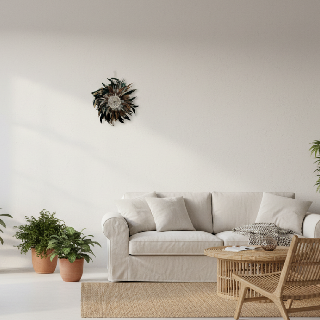 Small handcrafted Balinese Handcrafted Balinese Juju Hat Wall Hanging  with dark feathers and cowrie shell centre, 30–35cm, styled in a bright coastal boho living room with white sofa and rattan furniture

