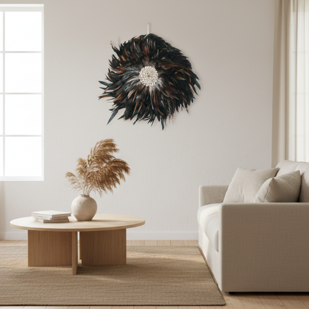  Handcrafted Balinese Juju Hat wall hanging with layered dark feathers and a cowrie shell centre, styled on a white wall in a boho-inspired living room. Decorative boho wall décor measuring 40–50cm.