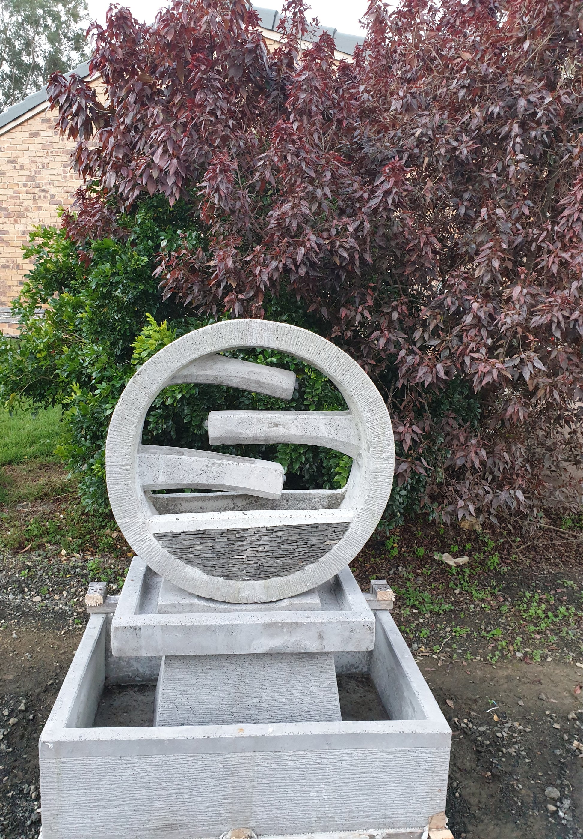Gray stone sculpture with circular design in an outdoor setting