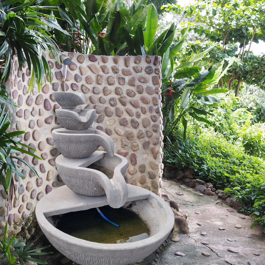 Outdoor water fountain with a pebble wall and greenery