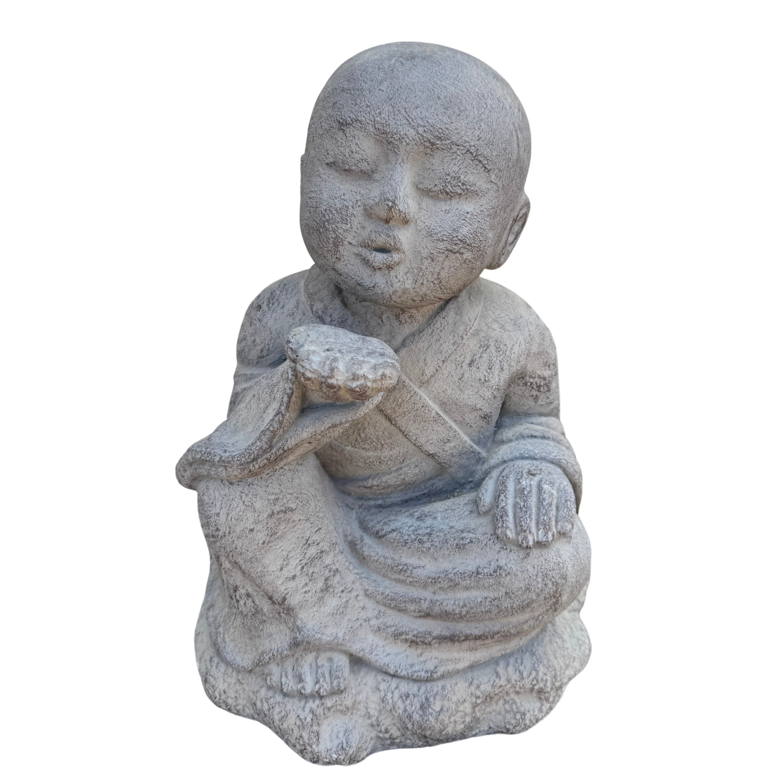 Grey kiss-blowing monk statue seated with one palm raised near its lips and a weathered textured finish