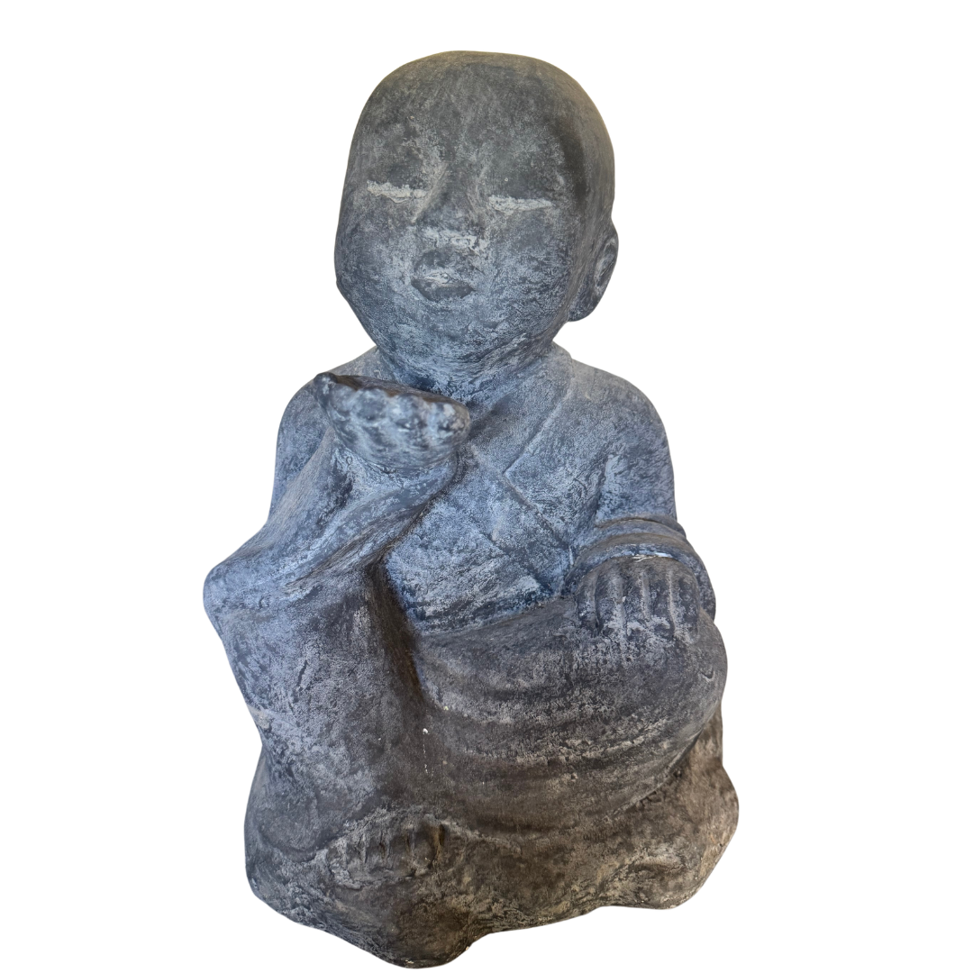 rustic gray of a grey seated figurine showing textured detailing and folds across the robes.