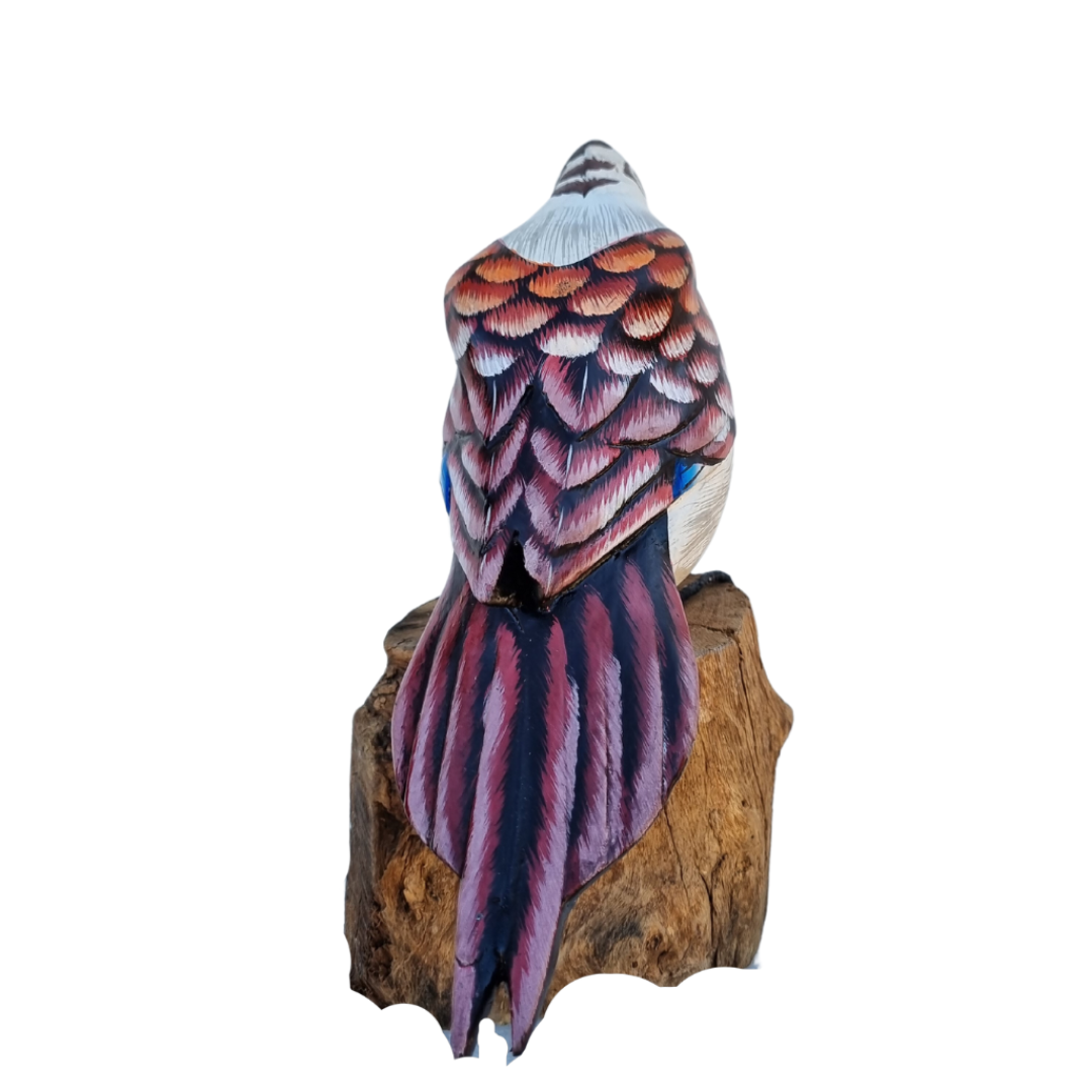 Hand-carved wooden Kookaburra bird perched on a solid natural wood base. The bird is detailed and lifelike, with carved feathers and a realistic shape. The backdrop is plain white, highlighting the sculpture’s texture and natural wood tones back view