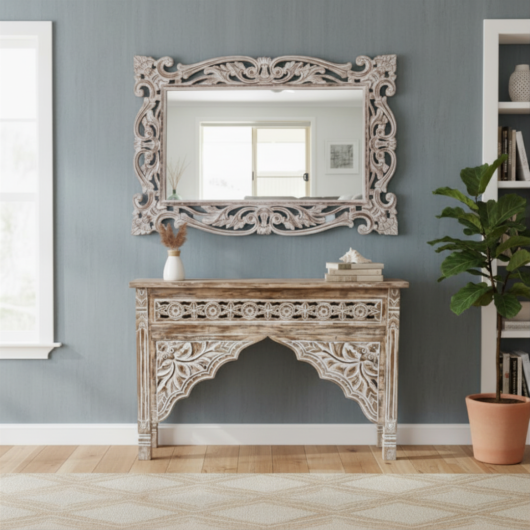 Decorative console table with ornate carvings and matching mirror against a gray wall.