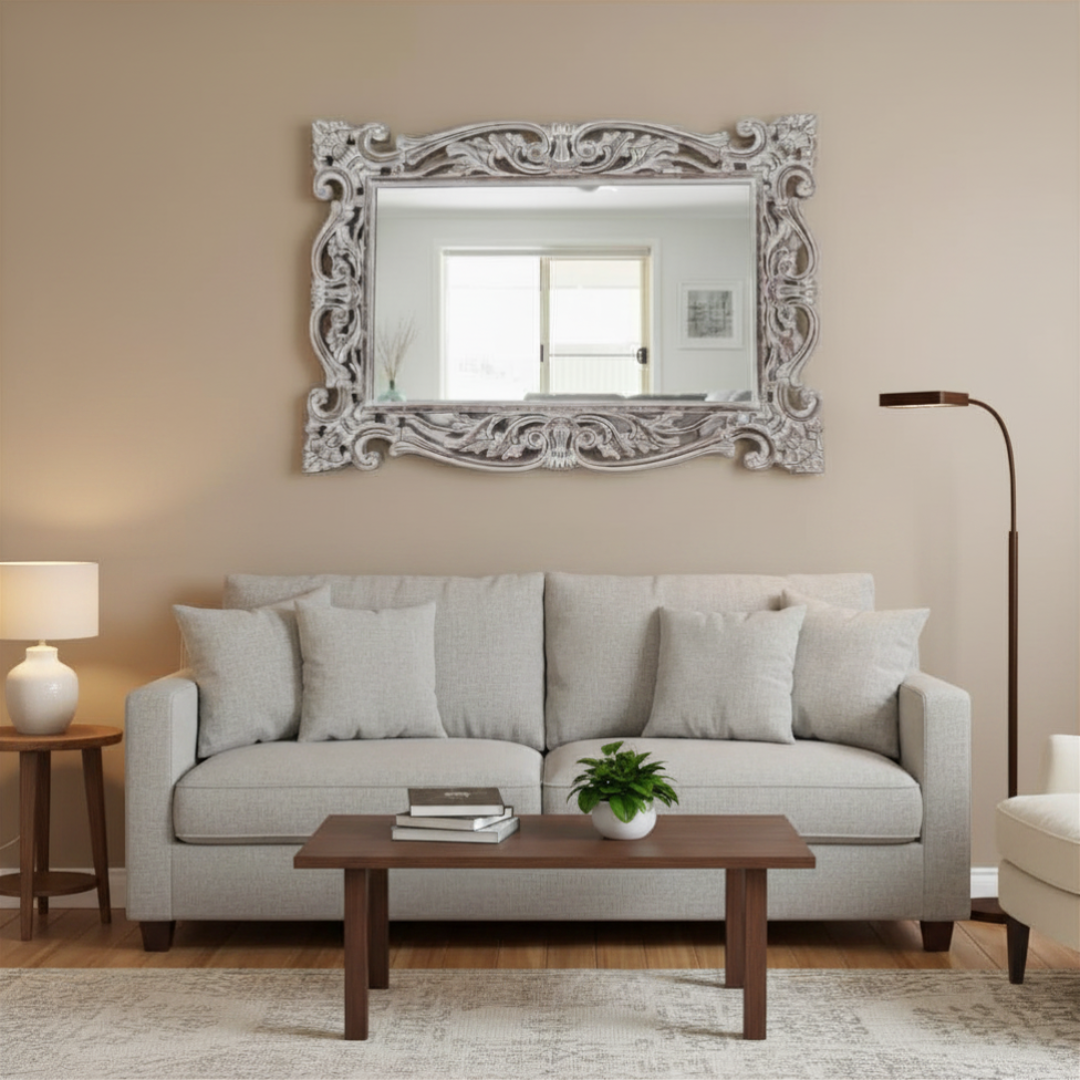Living room with a gray sofa, wooden coffee table, decorative mirror, and lamp.
