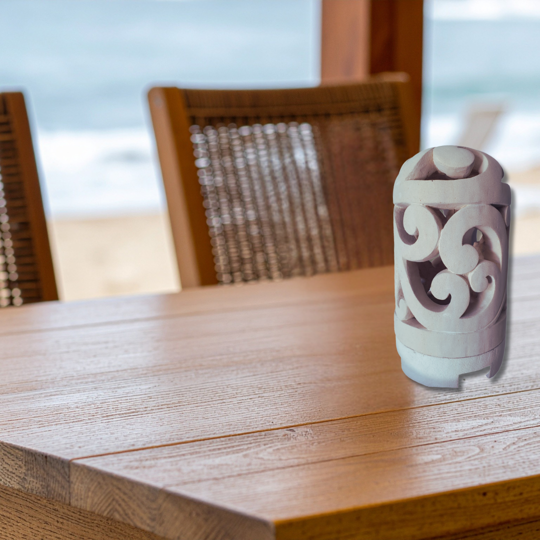 Decorative ceramic lantern on a wooden table with blurred chairs and background