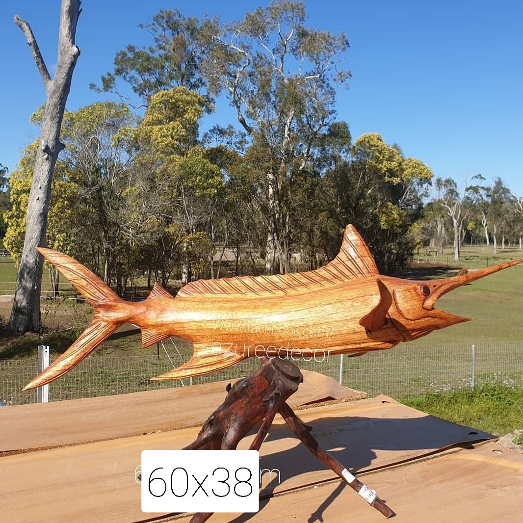 Wooden fish sculpture on a stand with trees in the background
