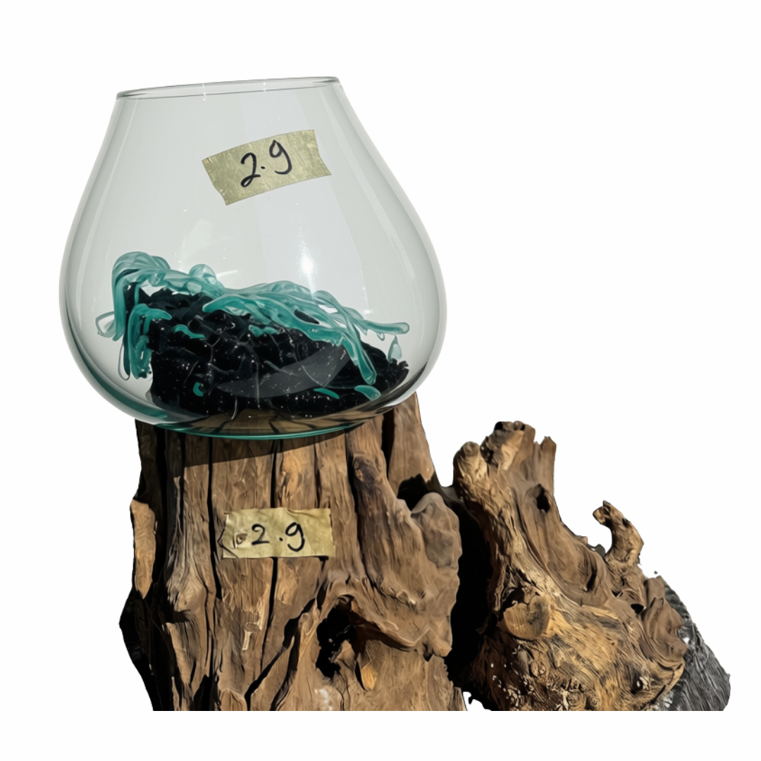 A clear glass bowl or vase displayed on a rustic wood pedestal against a white background. Inside the bowl are black and teal shredded material, likely decorative fiber or plant material.