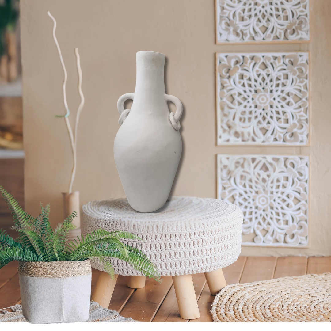 White vase on a woven stool with decorative wall panels in the background