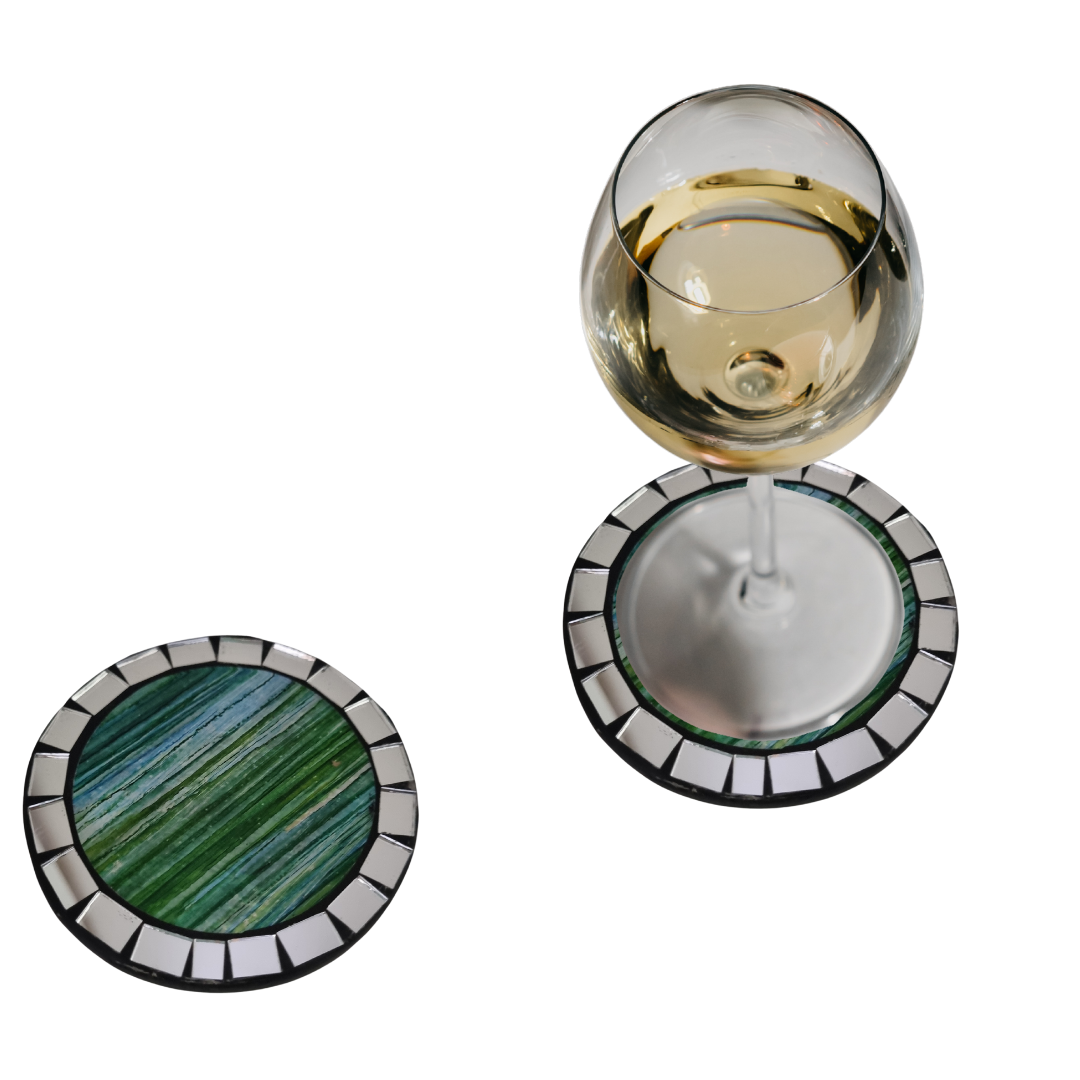 A set of round mosaic drink coasters in various colors, displayed alongside glasses of white wine 