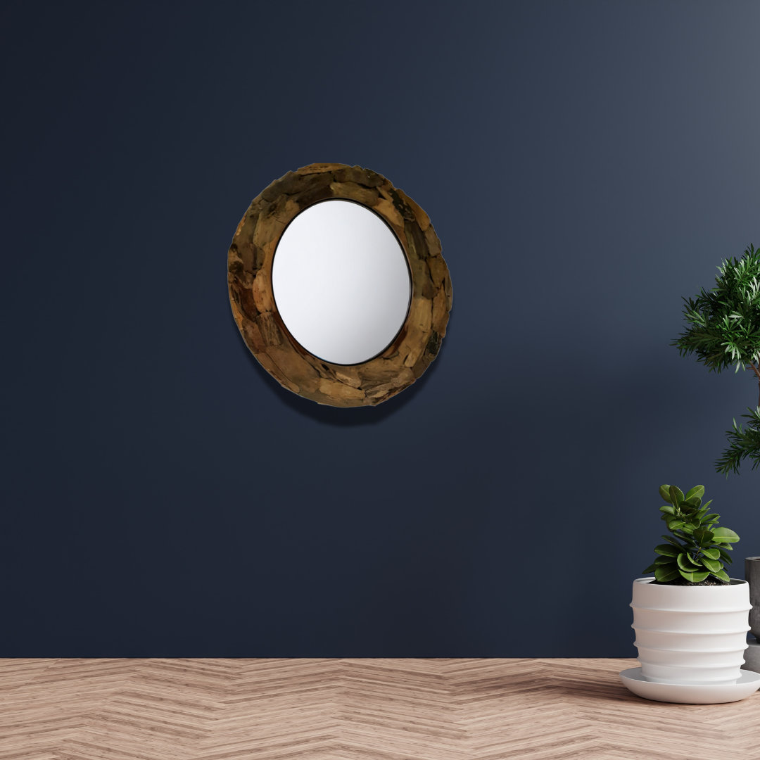 Round wooden-framed mirror on a dark blue wall with a potted plant on a wooden surface.