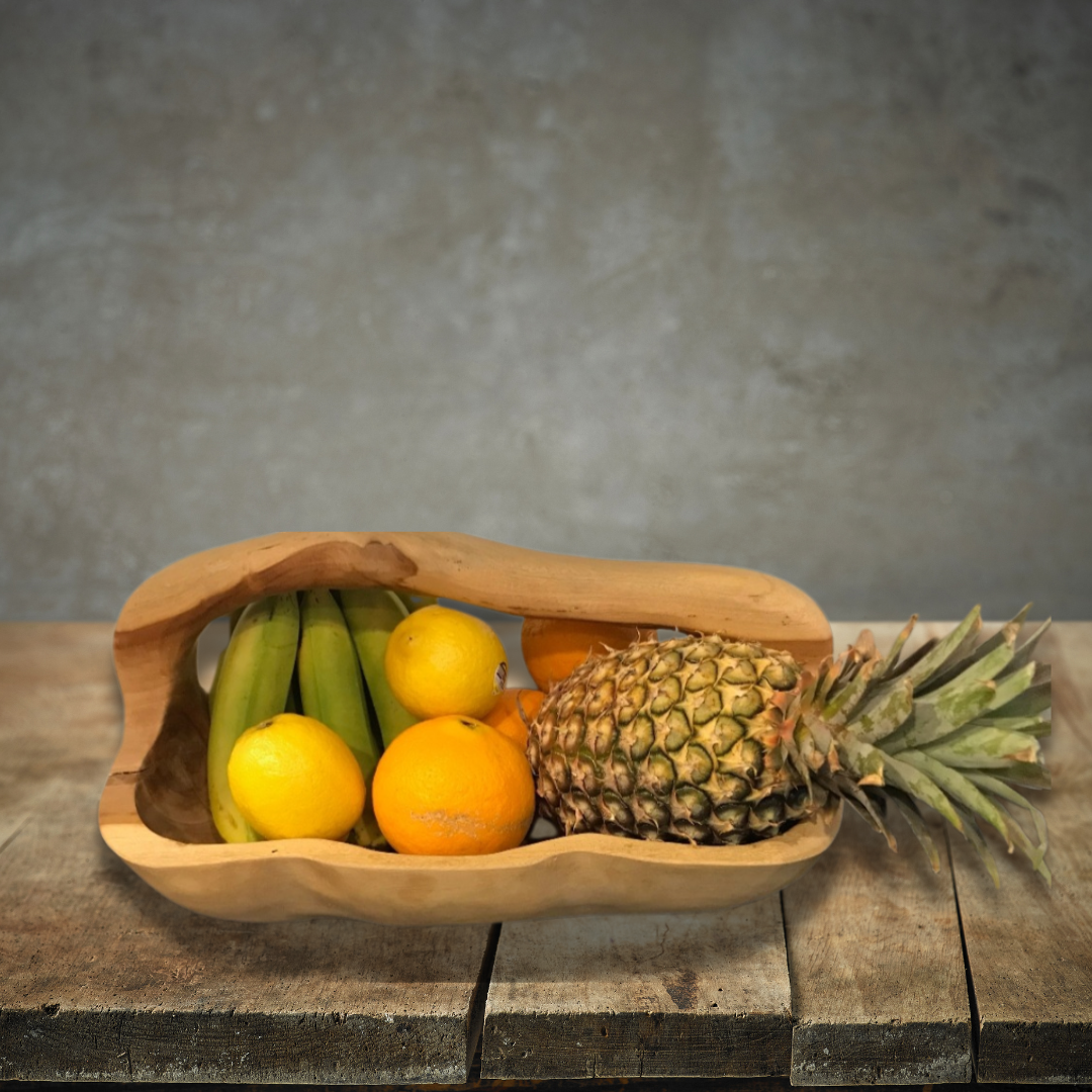 Wooden fruit basket with pineapple, oranges, and bananas on a wooden surface with a gray background