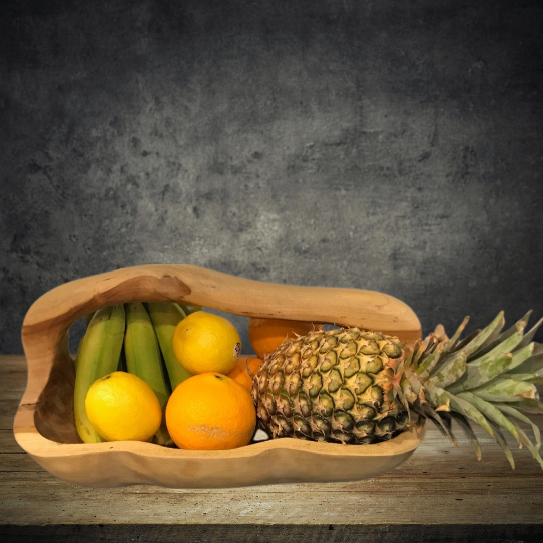 Wooden basket with fruits including bananas, lemons, and a pineapple on a wooden surface with a dark background.