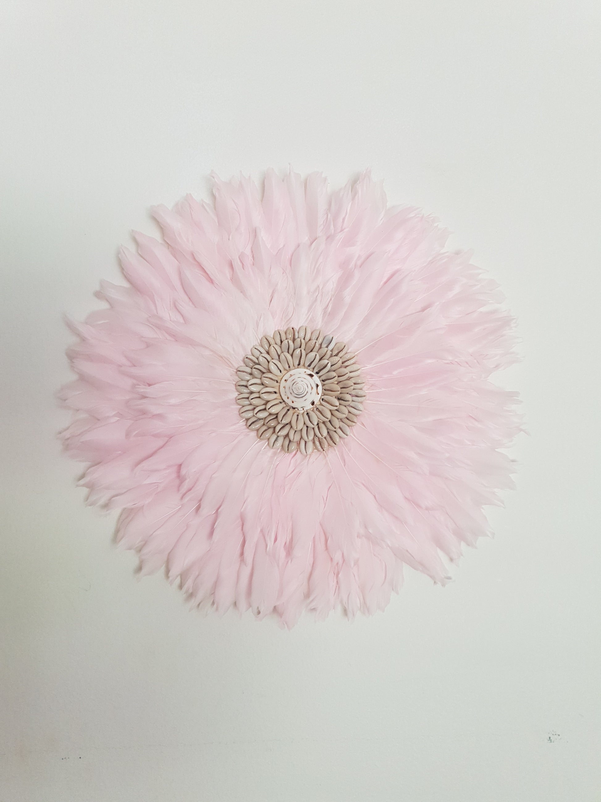 Pink feathered headband with a central pearl-like element on a light gray background