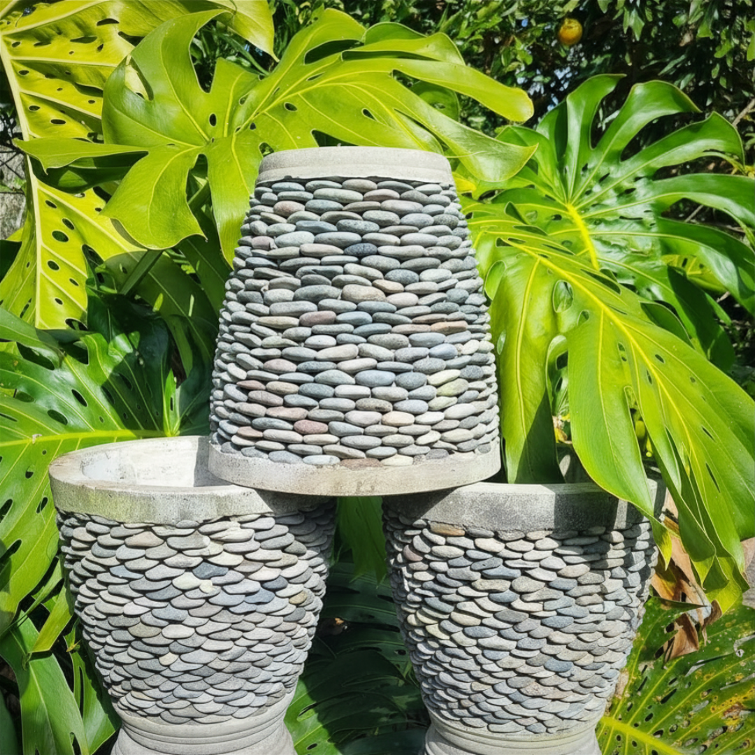 Three stone-textured vases in a garden setting with green foliage.