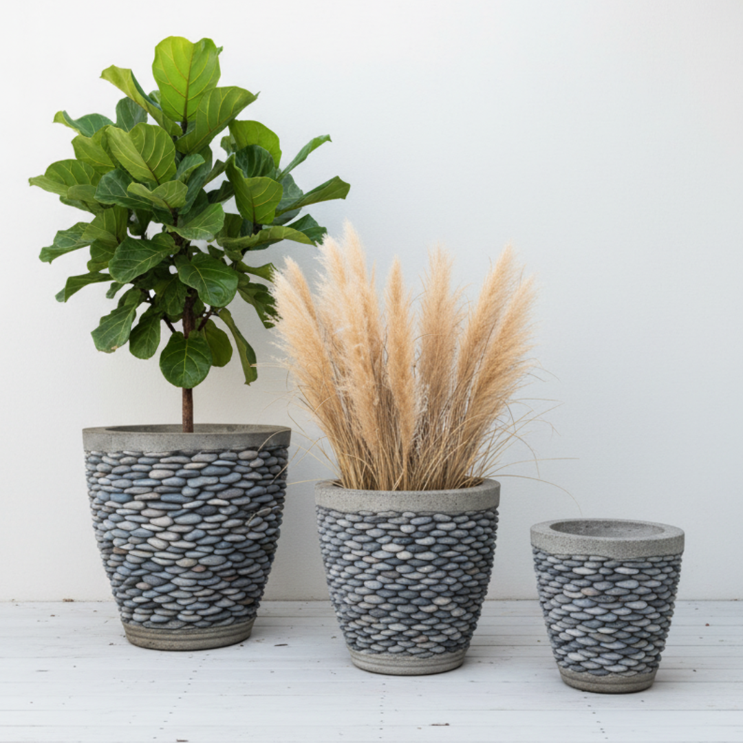 Pebble Concrete Pot Indoor Outdoor — three sizes grouped together in a tropical garden setting with monstera leaves