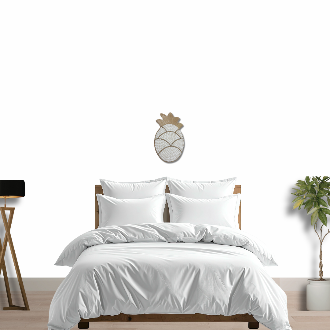 White bedding set on a bed with a decorative Pineapple Shell Wall Art piece above it.