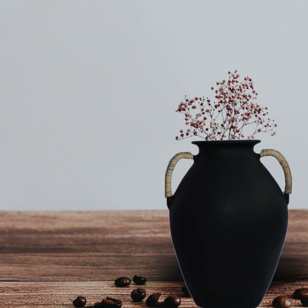 Black vase with dried flowers on a wooden surface