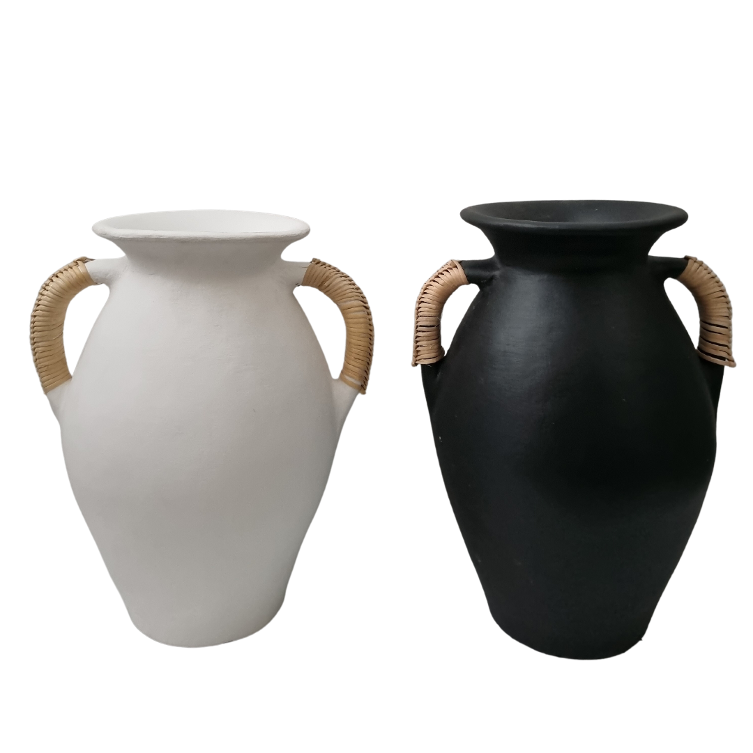 Two terracotta vases with rattan handles, one painted in black and the other in white, against a plain background.