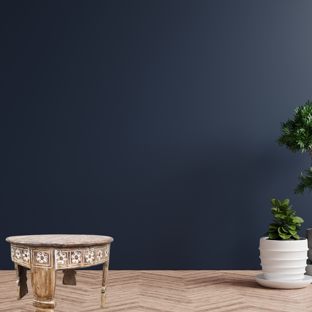 wooden coffee table on natural floor with blue wall and a white pot and plant on the far right 